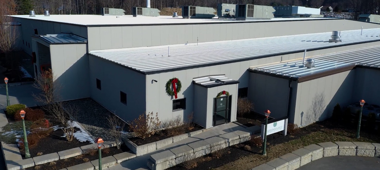An aerial view of a modern commercial building with a large wreath above the entrance.